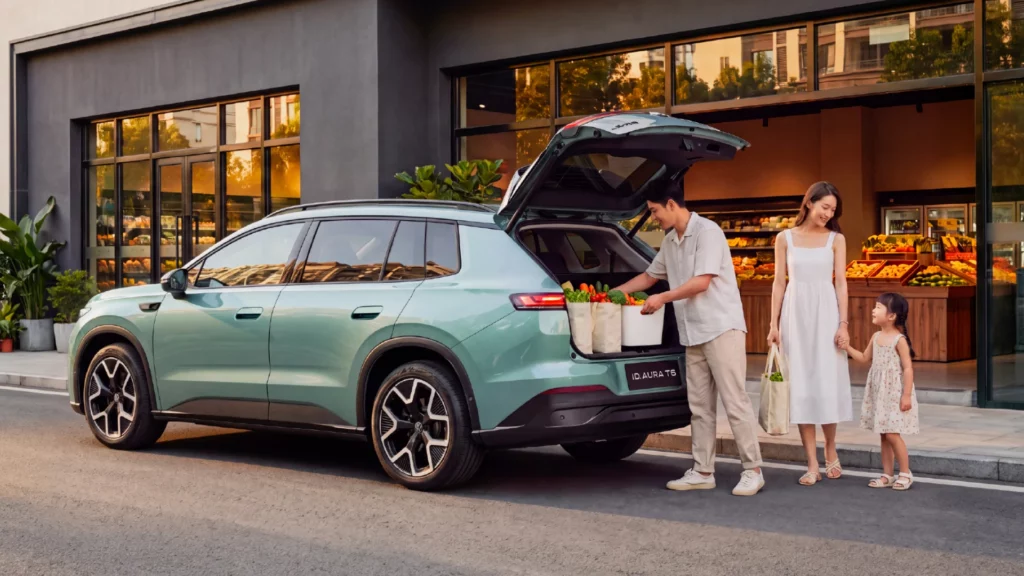 Rodzina pakuje zakupy do bagażnika elektrycznego Volkswagena ID. Aura T6 przed sklepem